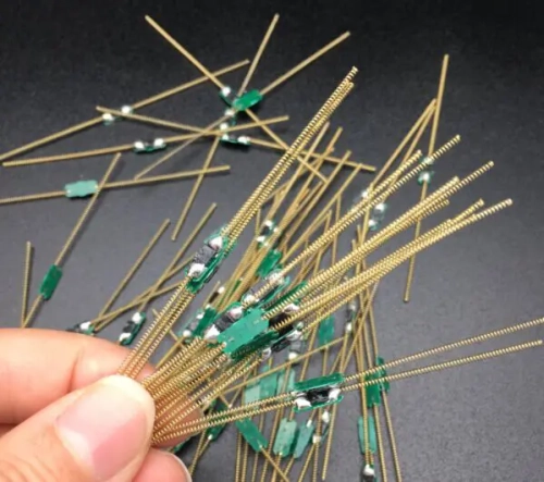 Slender spring-antenna transponders with small green central assemblies.