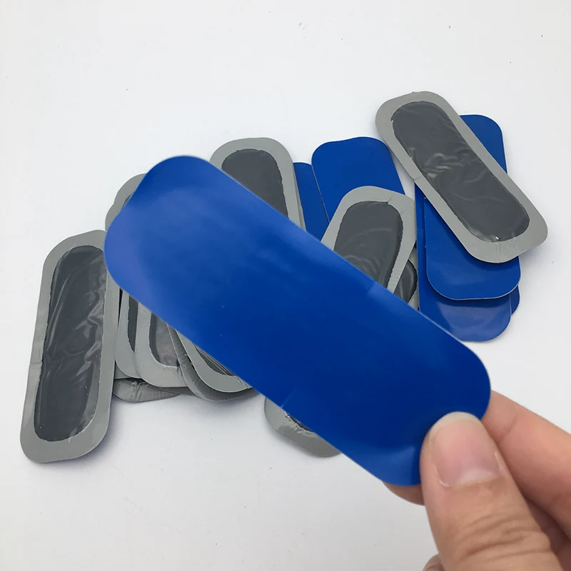 Blue and grey elongated tyre patches, with one blue patch held in a hand.